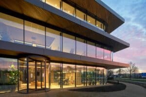Modern kantoorgebouw met glazen gevel en draaideur, avondlicht